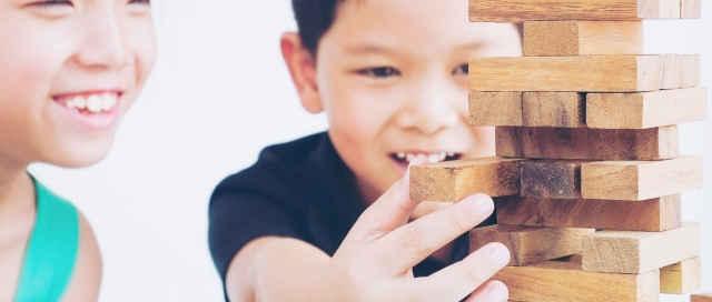 Children are playing a wood blocks tower game for practicing their physical and mental skill