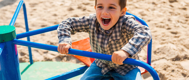 Happy child playing enthusiastically on colourful playground equipment, showing joy and excitement