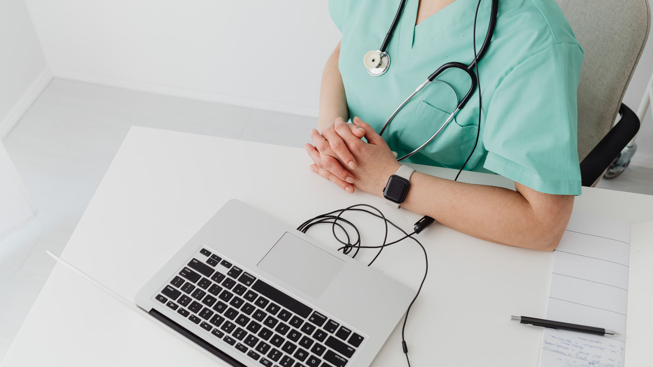 Doctor in green scrubs sitting in front of a laptop