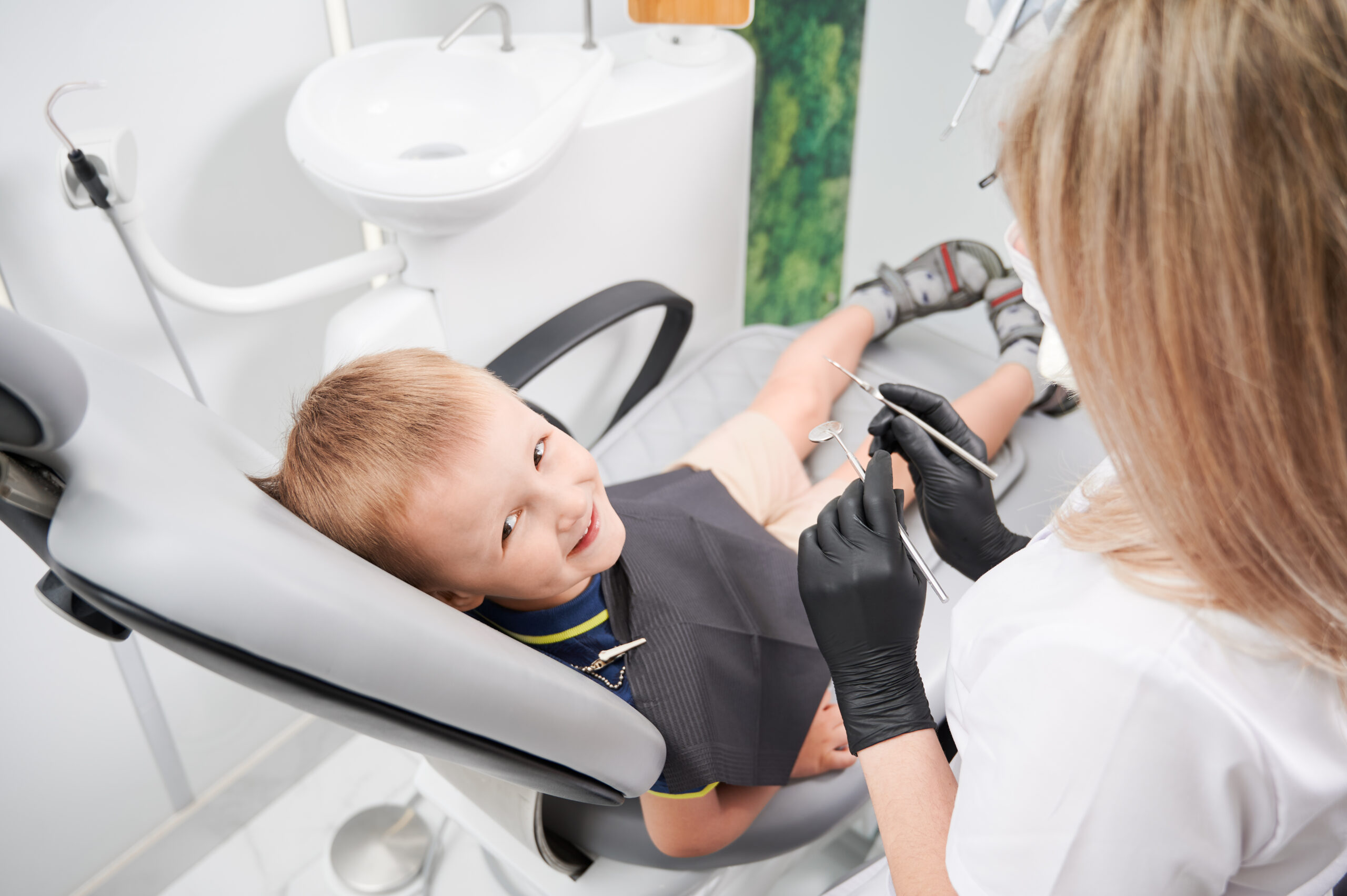 Cheerful little boy sitting in dental chair in dental office.